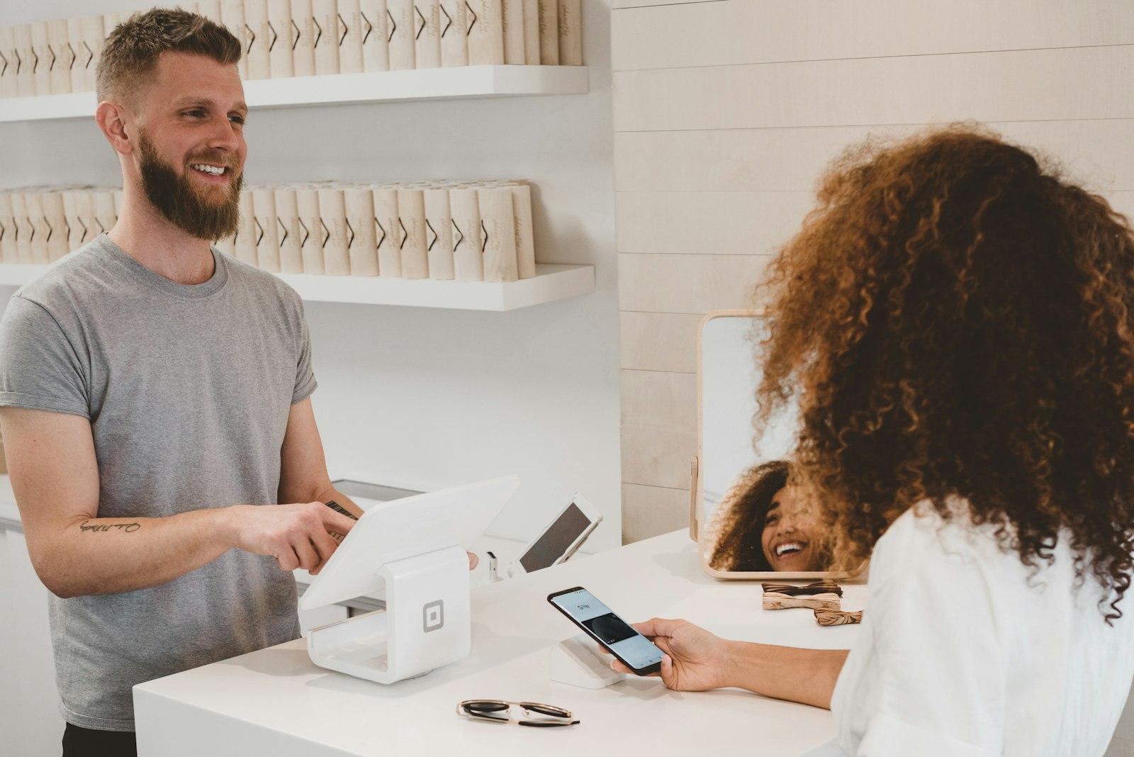 A small business owner helping a customer check out at a bright, modern shop counter